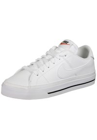 Bílé kožené tenisky s polstrovaným límcem, černou gumovou podešví a bílými tkaničkami. Na jazyku je malá červená značka Nike.