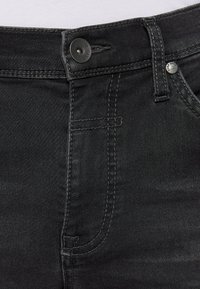 Schwarze Jeans aus Denim mit einem standardmäßigen Knopfverschluss, kontrastierendem Nähen und einer glatten Textur, im klassischen Schnitt und ohne sichtbare Muster.