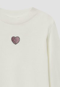 Lichtcrème sweatshirt met een kleine roze gebroken hart geborduurd op de borst. Glad stof met een klassieke ronde halslijn.