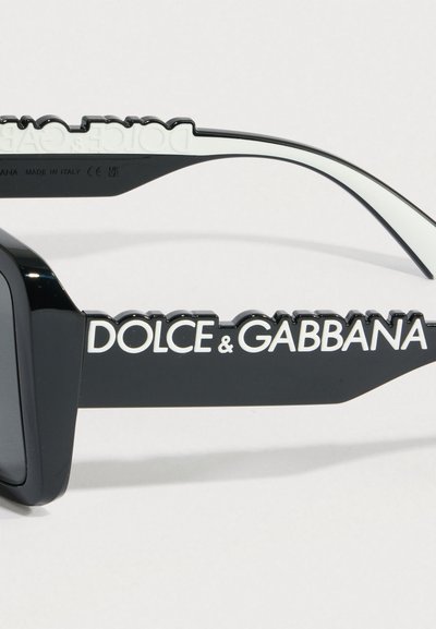 Mustad atseetaadist päikeseprillid massiivsete ristkülikukujuliste raamidega. Külgedel on valge logo ja kumerad otsad. Sile pind viimistlus.