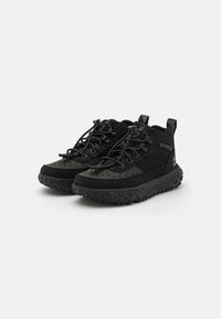 Scarpe da esterno nere con tomaia in rete e dettagli in suede, dotate di suola in gomma testurizzata e perforazioni per la ventilazione.