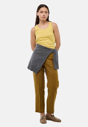 Débardeur jaune, écharpe tricotée grise autour de la taille, pantalon en lin beige et chaussures marron clair. Design simple avec une coupe décontractée et une palette de couleurs neutres.
