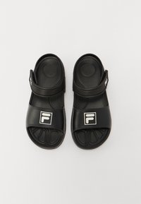 Mustad musta kummist sandaalid laia rihmaga, millel on valge logo. Tekstureeritud tald ja reguleeritav velcro rihm kindla istuvuse tagamiseks.