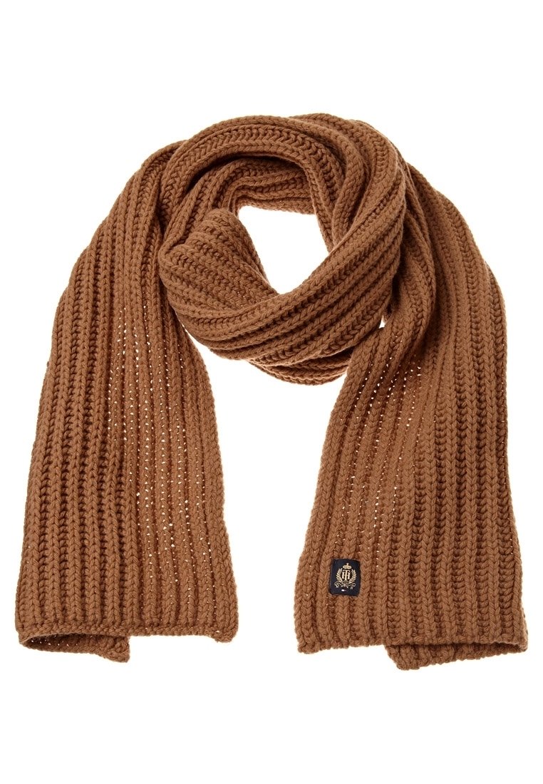 Écharpe en laine brune tricotée avec un motif côtelé, bouclée de manière lâche avec une petite étiquette de marque noire et dorée cousue près d’une extrémité.