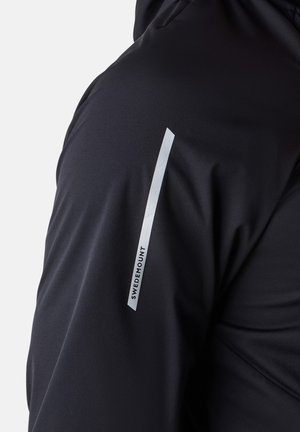 Giacca tecnica nera caratterizzata da una texture liscia, una forma aderente e una striscia verticale bianca prominente con il testo "SWEDEMOUNT" sulla manica.