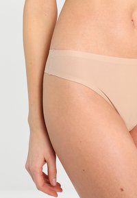 Nude låg midja trosa med en slät textur och sömlös design. Har en mjuk midjeband och minimal bakdäckning för komfort.