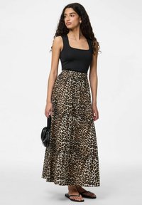 Melnā bez piedurknēm blūze apvienota ar garu, leopardu raksta svārku. Svārks ir plūstošs ar elastīgu jostasvietu un sānu šķēlumiem.