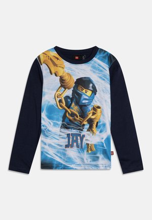 Dziecięca granatowa koszula z długim rękawem z postacią LEGO Ninjago Jay trzymającą złote łańcuchy, na tle elektrycznie niebieskiego tła.