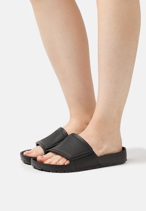 Les sandales noires à glissière présentent des brides texturées et une semelle rembourrée. Le design inclut un bout ouvert et une base plate pour plus de confort.