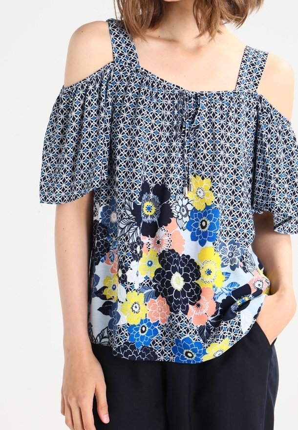 Bluzka w kwiatowy wzór z odkrytymi ramionami, w niebiesko-biała-żółtej kolorystyce, wykonana z luźnego, miękkiego materiału.