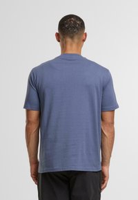 Koszulka z krótkim rękawem z miękkiej niebieskiej bawełny. Design z okrągłym dekoltem i prostym krojem. Gładka tekstura, minimalne zdobienia i brak grafiki.