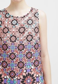 Dámský top bez rukávů s barevným geometrickým potiskem v odstínech růžové, černé, bílé a modré. Kulatý výstřih a lehká látka.