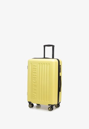 Żółta walizka twarda z żłobioną teksturą, czarnym zamkiem błyskawicznym i teleskopową rączką. Posiada cztery kółka dla łatwości poruszania się oraz markowy przód.