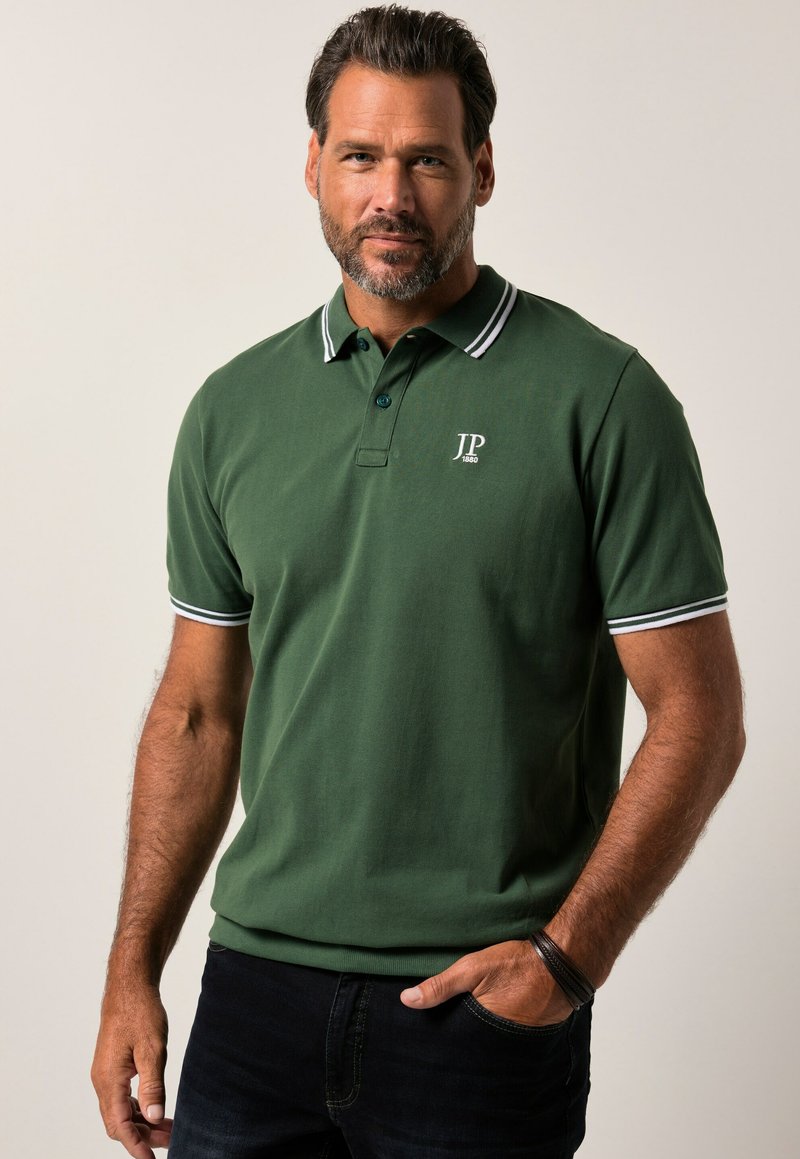 Polo verde in cotone con colletto classico, dotato di accenti a righe bianche sul colletto e sulle maniche, e un piccolo logo sul petto.