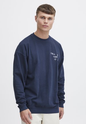 Navy blue sweatshirt in soft cotton, featuring a round neckline and long sleeves. “Tell it like it” printed in white on the front.