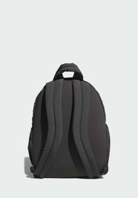 Mochila negra con correas acolchadas, asa superior y forma redondeada. Textura de tela lisa, sin patrones ni herrajes visibles.