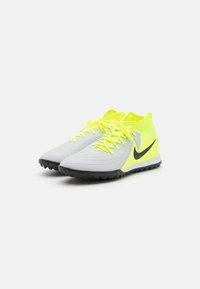 Zapatillas de fútbol grises y amarillo neón con parte superior texturizada, detalles en negro y suela de goma moldeada para tracción.