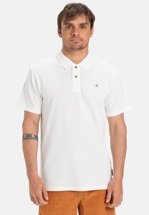 T-shirt polo blanc avec un col classique, trois boutons marron et un petit logo sur la poitrine. Manches courtes et texture lisse.