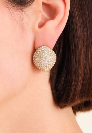 Pendientes de botón con tono dorado en forma redondeada y acolchonada, adornados con múltiples pequeñas piedras de imitación claras, creando una superficie texturizada.