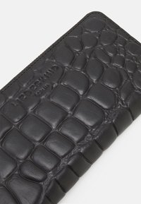 Portefeuille en cuir noir avec un motif texturé de peau de crocodile, arborant un logo en relief et un design épuré et minimal.