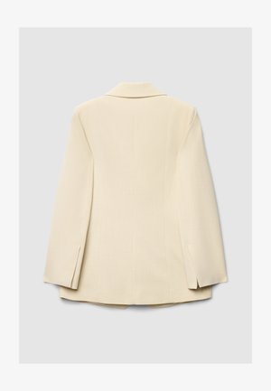 Blazer beige ajusté avec un col cranté, des manches longues et des côtés fendus, confectionné dans un tissu lisse avec une texture subtile.