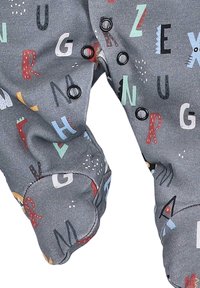 Grauer Stoff, bedeckt mit verspielten Buchstaben und Symbolen in verschiedenen Farben. Mit abgerundeten Bündchen und Druckknöpfen zum Schließen. Weiche Textur.