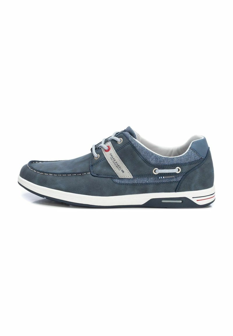 Zapatos casuales en azul marino hechos de cuero y malla, con un panel gris en contraste, suela blanca y detalles decorativos en los cordones.