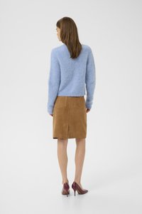 Lyseblå fluffy genser med v-hals, sammen med en brun semsket blyantskjørt og maroon høyhælte sko, sett fra ryggen.