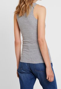 Top intimo grigio a coste con design aderente, senza maniche e morbido al tatto, abbinato a jeans in denim blu.