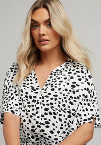 Camicia button-up bianca e nera con scollo a V e maniche corte, caratterizzata da un motivo a stampa animale textured.