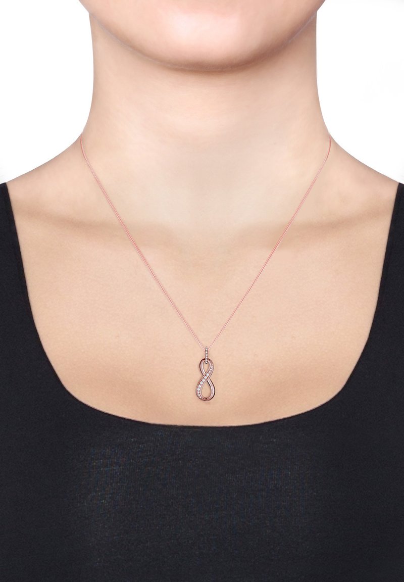 Rose gold uendelighedsøsknig med et snoet design og klare cubic zirconia accenter på den ene side, hængende fra en delikat kæde.