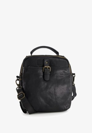 Zwarte leren tas met een textuurafwerking, een bovenhandvat, een verstelbare schouderriem, messing hardware en een ritssluiting.