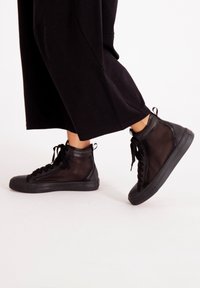 Svarta högskurna sneakers med en meshövre, rund tå och gummisulor med texturerad detalj och snören.