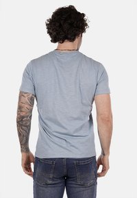 T-shirt azzurro chiaro a maniche corte con collo tondo, realizzato in materiale morbido. Presenta una vestibilità comoda e una leggera texture. Vista posteriore mostrata.