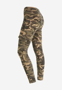 Leggings mimetici con un design aderente, caratterizzati da diverse tonalità di verde e marrone, tessuto testurizzato e tasche cargo laterali.