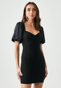 Zwarte mini-jurk met een aansluitende silhouet, voorzien van pofmouwen en een sweetheart-halslijn. Geweven stof en naaddetails.