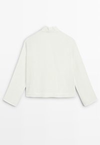 Hvid langærmet cropped top med høj hals, vist fladt bagfra på en hvid baggrund.