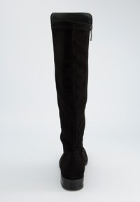 Bota de cuero de ante negra, hasta la rodilla, con un acolchado de cuero suave en la parte superior, cremallera lateral y una suela de goma negra resistente. Tacón plano.