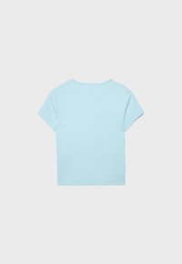 Jasnoniebieska, gładka koszulka z krótkim rękawem, ułożona na płasko, pokazująca tylną stronę z okrągłym dekoltem na białym tle.