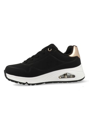 Baskets noires avec tige en synthétique, semelle intermédiaire blanche, accent doré au niveau du talon, texture perforée et unité de coussinage à air visible.