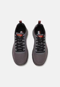 Gray athletic shoes with a breathable mesh upper, black laces, and a contrasting red accent on the heel and tongue. Lightweight design.