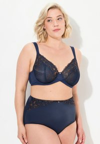 Laivansinis alusvaatekokonaisuus, joka sisältää rintaliivit, joissa on läpinäkyvää pitsiä, sekä korkeavyötäröiset alushousut, joissa on kukkakuviota ja kultaisia yksityiskohtia.