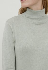 Light gray turtleneck sweater made of soft knit fabric; features a ribbed collar and subtle texture. No visible patterns or hardware.