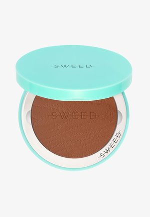 Compatto di bronzer con coperchio turchese, presenta una polvere marrone testurizzata all'interno. "SWEED" è impresso sulla polvere e stampato sul coperchio.