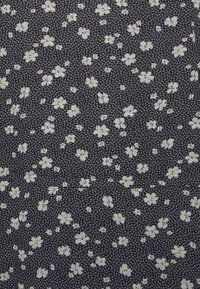 Tecido floral com pequenas flores brancas com centros amarelos sobre um fundo azul marinho escuro. O padrão é denso com uma textura sutil.