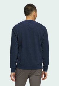 Marine genser med rund hals, ribbestrikkede mansjetter og nederkant. Laget av mykt stoff med en jevn tekstur. Har et enkelt design og minimale detaljer.