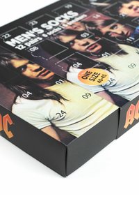 Imballaggio in scatola nera per calzini da uomo, contenente 12 paia e 1 paio di pantofole. Presenta numeri, volti e un adesivo arancione "Taglia Unica".