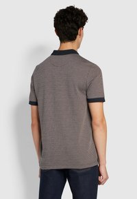 Polo à manches courtes avec un motif en losanges texturé, col et finitions des manches bleu marine, dans des couleurs neutres. Le tissu a une finition lisse.