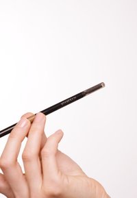 Crayon à sourcils noir avec un couvercle en brosse transparente, présentant un design mince et cylindrique et des poils texturés pour entretenir les sourcils.