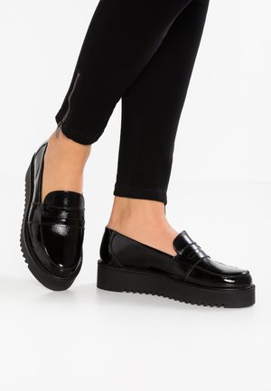Mocassins en cuir verni noir avec une semelle plateforme épaisse et une semelle extérieure en caoutchouc texturé. Des surpiqûres décoratives près de l'avant ajoutent un design subtil.